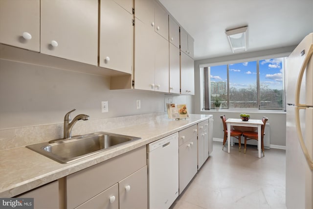 kitchen with white appliances, light countertops, a sink, and baseboards