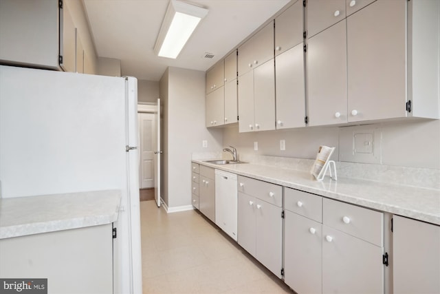 kitchen with light countertops, white appliances, a sink, and baseboards