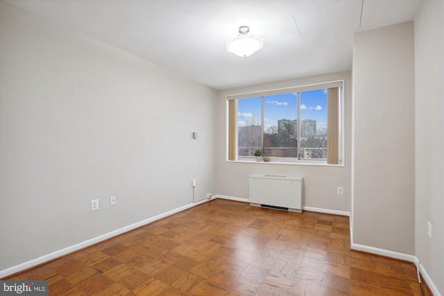 empty room with radiator heating unit, baseboards, and a city view