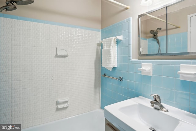 bathroom with shower / bath combination, tile walls, and a sink