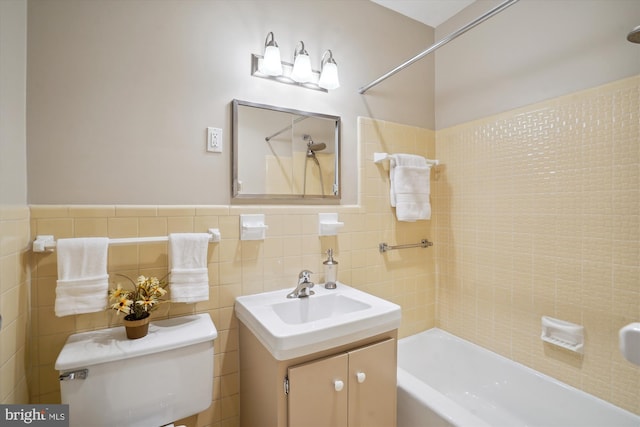 bathroom featuring toilet, vanity, tile walls, wainscoting, and washtub / shower combination