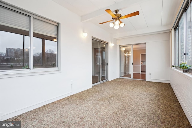 interior space featuring ceiling fan with notable chandelier, beamed ceiling, and a healthy amount of sunlight