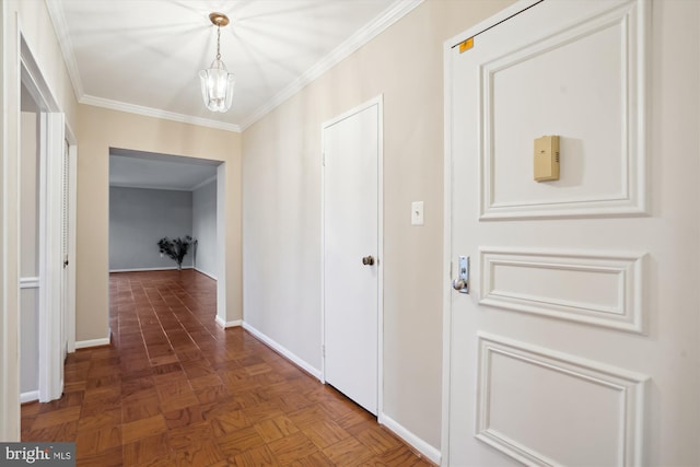 hall with a chandelier, ornamental molding, and baseboards