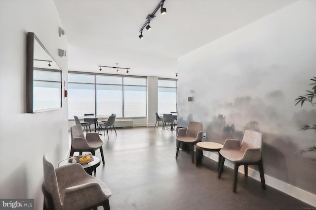 sitting room with rail lighting, concrete floors, and baseboards