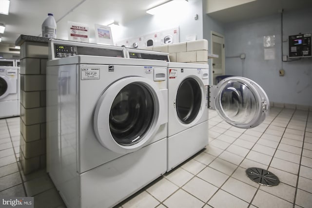 community laundry room featuring washing machine and dryer and light tile patterned floors