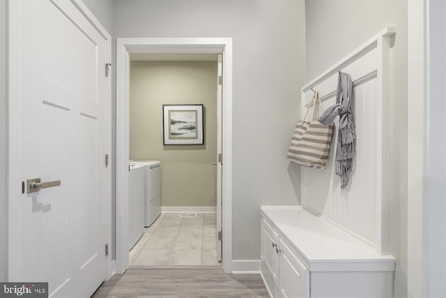 mudroom featuring light wood-type flooring, washing machine and dryer, and baseboards