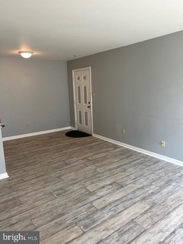 spare room with baseboards and wood finished floors