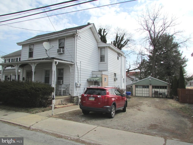 view of front of property with covered porch, a detached garage, and an outdoor structure