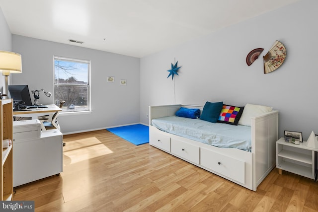 bedroom with light wood-type flooring, visible vents, and baseboards