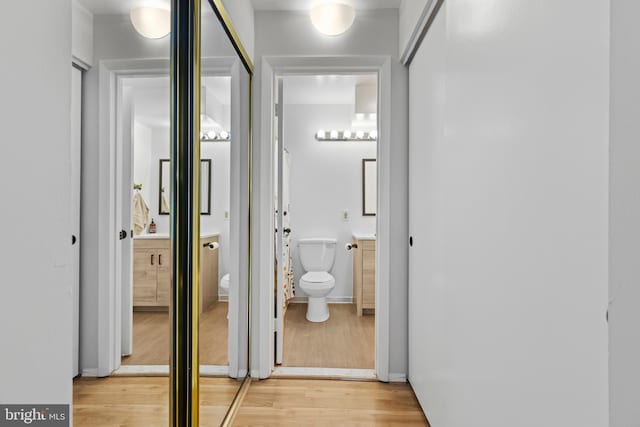 corridor with light wood-type flooring and baseboards