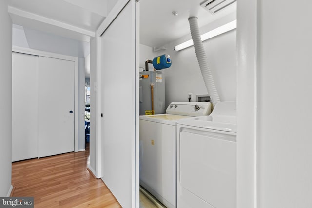 laundry room with laundry area, visible vents, water heater, independent washer and dryer, and light wood finished floors