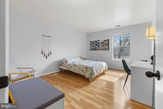 bedroom with light wood-type flooring, visible vents, and baseboards