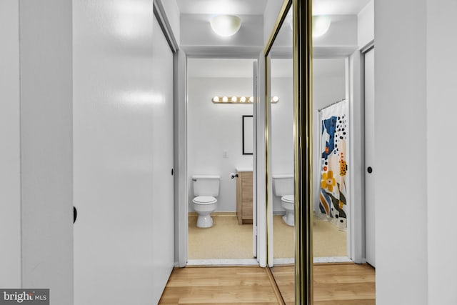 bathroom featuring vanity, wood finished floors, toilet, and baseboards