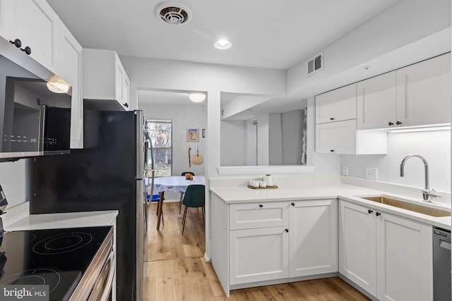 kitchen with visible vents, light wood-style flooring, electric range, white cabinets, and a sink