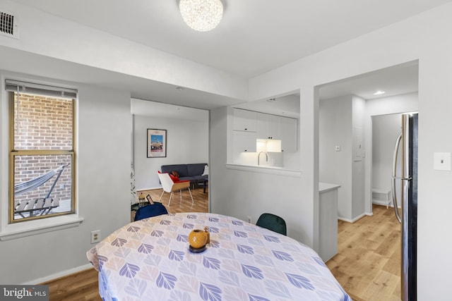 dining room featuring light wood-type flooring, visible vents, and baseboards