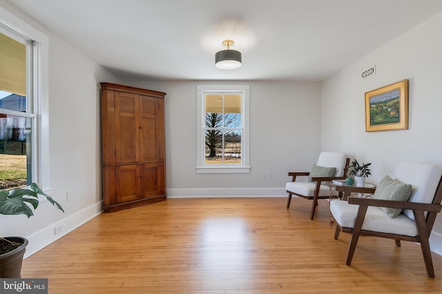 sitting room with light wood finished floors, visible vents, and baseboards