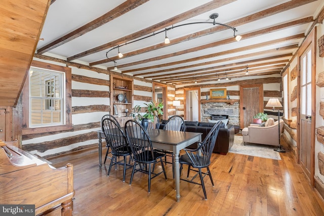 dining area featuring beamed ceiling, a fireplace, and light wood-style floors