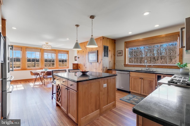 kitchen with stainless steel appliances, a healthy amount of sunlight, a sink, and light wood finished floors