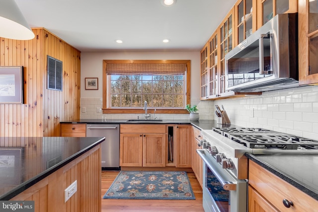 kitchen featuring light wood-style floors, tasteful backsplash, stainless steel appliances, and a sink