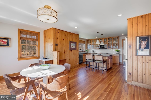 dining area with light wood-style floors, recessed lighting, and wooden walls