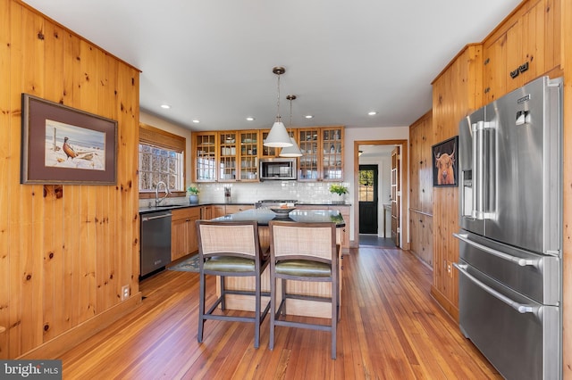 kitchen featuring appliances with stainless steel finishes, a sink, light wood-style flooring, and a center island