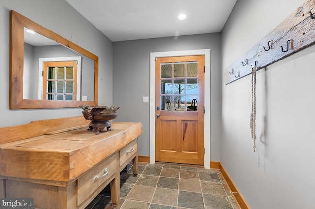 entryway featuring stone finish flooring and baseboards