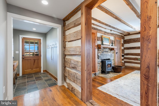 foyer entrance featuring recessed lighting, dark wood finished floors, a wood stove, and baseboards