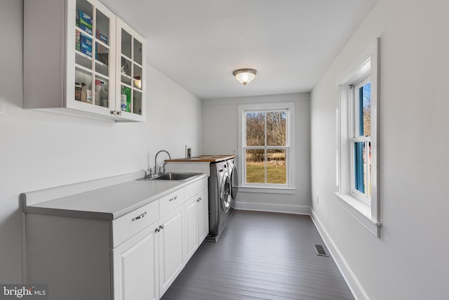 laundry room featuring cabinet space, baseboards, visible vents, washer and dryer, and a sink