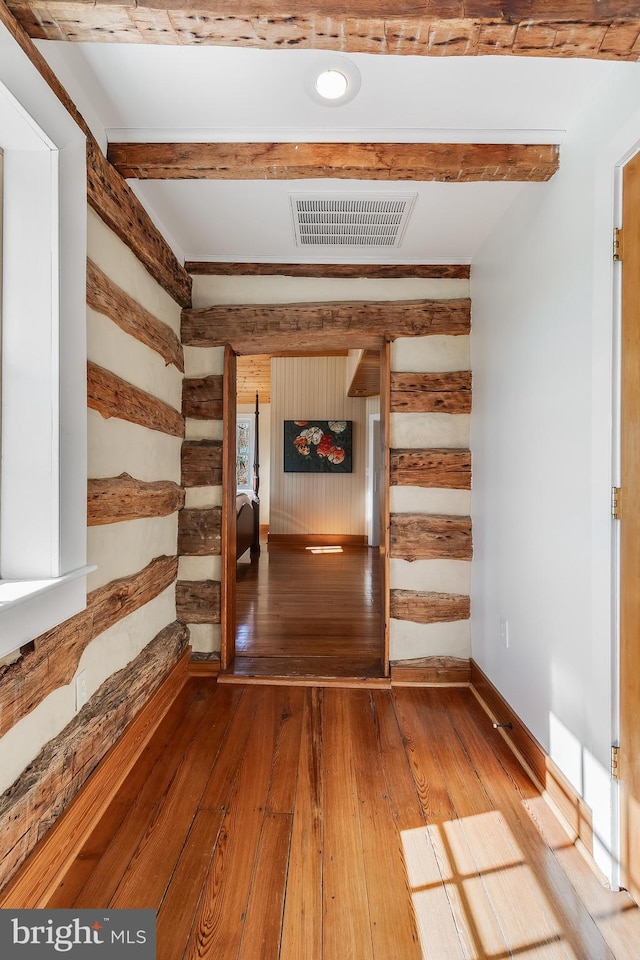 corridor with beam ceiling, wood-type flooring, visible vents, and baseboards