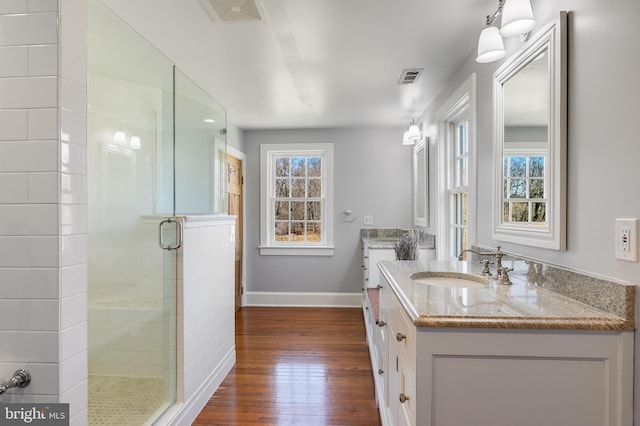 bathroom featuring wood finished floors, vanity, visible vents, baseboards, and a stall shower