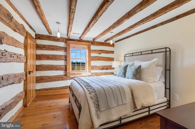 bedroom with beamed ceiling, wood-type flooring, and visible vents