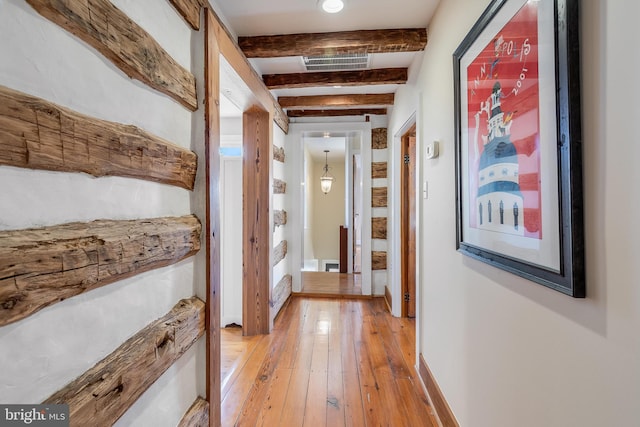 hall with light wood-style floors, beam ceiling, visible vents, and baseboards