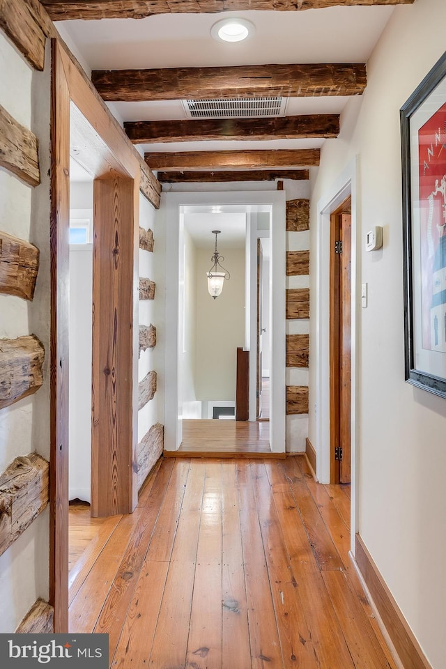 hall with baseboards, beam ceiling, and light wood-style floors