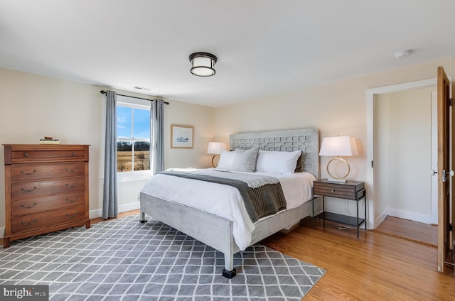 bedroom featuring wood finished floors, visible vents, and baseboards