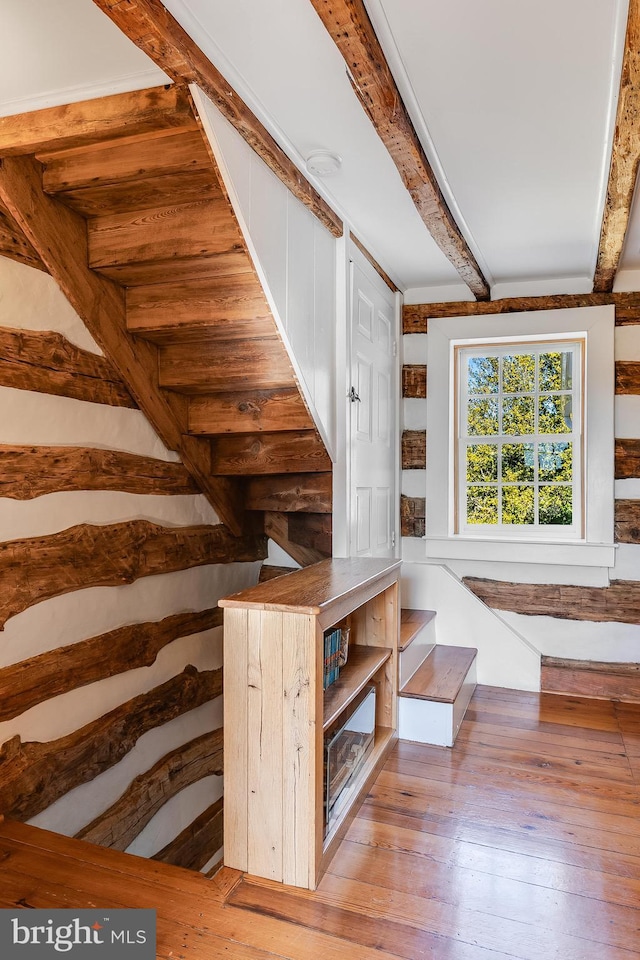 staircase featuring hardwood / wood-style flooring and beamed ceiling