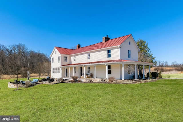 rear view of property with a yard, a standing seam roof, metal roof, and a porch