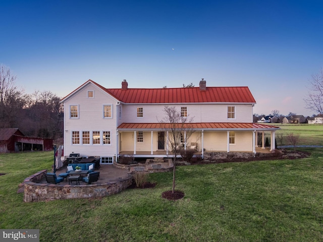 rear view of property featuring a standing seam roof, metal roof, and a lawn