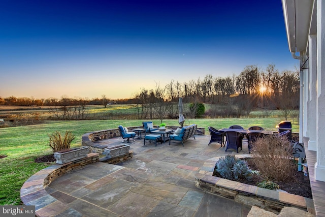 patio terrace at dusk with an outdoor living space with a fire pit and a lawn