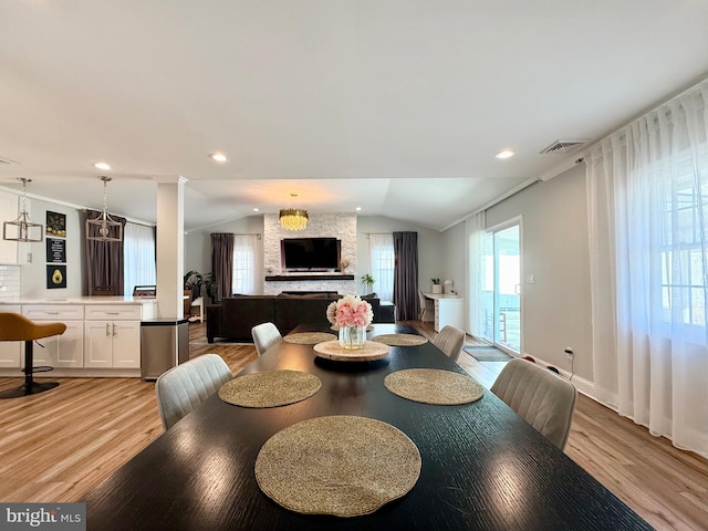 dining space with a wealth of natural light, visible vents, vaulted ceiling, and light wood finished floors