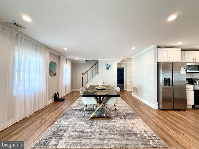 dining room with ornamental molding, stairway, visible vents, and light wood-style floors