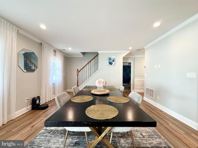 dining room featuring light wood finished floors, stairs, visible vents, and crown molding