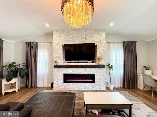 living room with lofted ceiling, recessed lighting, a stone fireplace, wood finished floors, and a chandelier