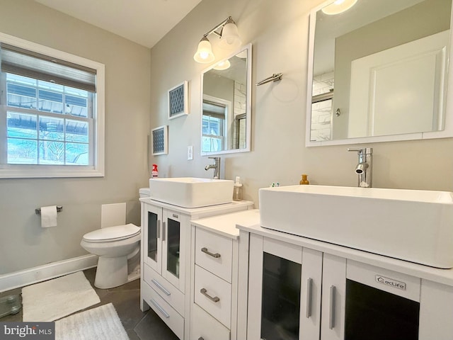 bathroom featuring toilet, baseboards, a wealth of natural light, and vanity