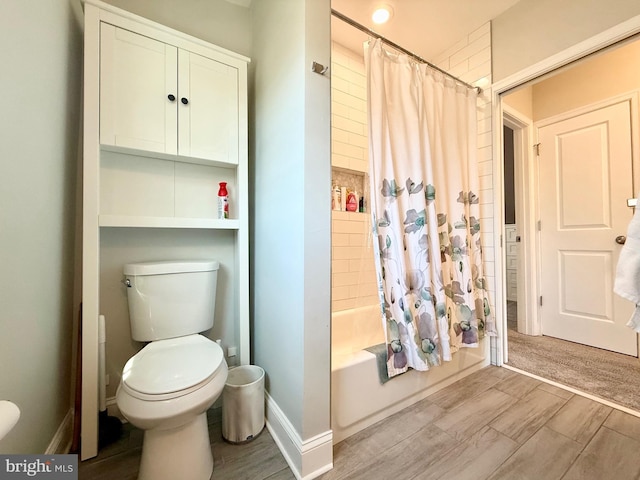 bathroom with wood finish floors, baseboards, toilet, and shower / bath combo with shower curtain