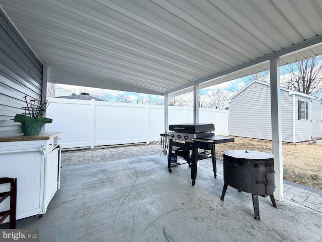 view of patio featuring an outbuilding, a storage shed, area for grilling, fence, and a carport