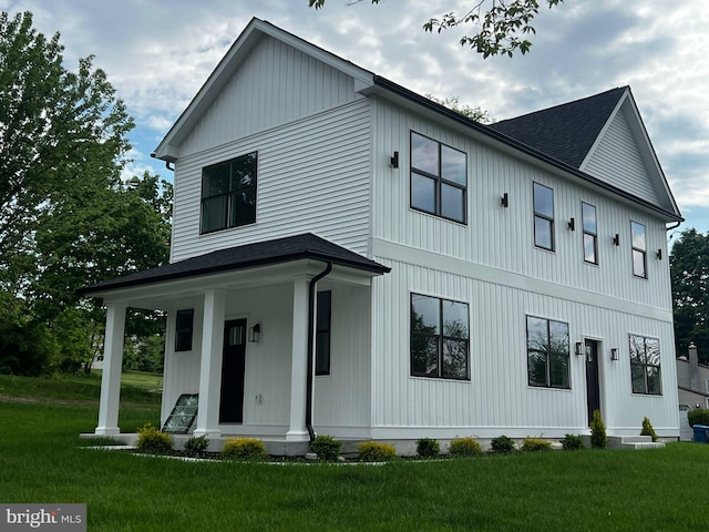 modern inspired farmhouse featuring a front lawn, a porch, and a shingled roof