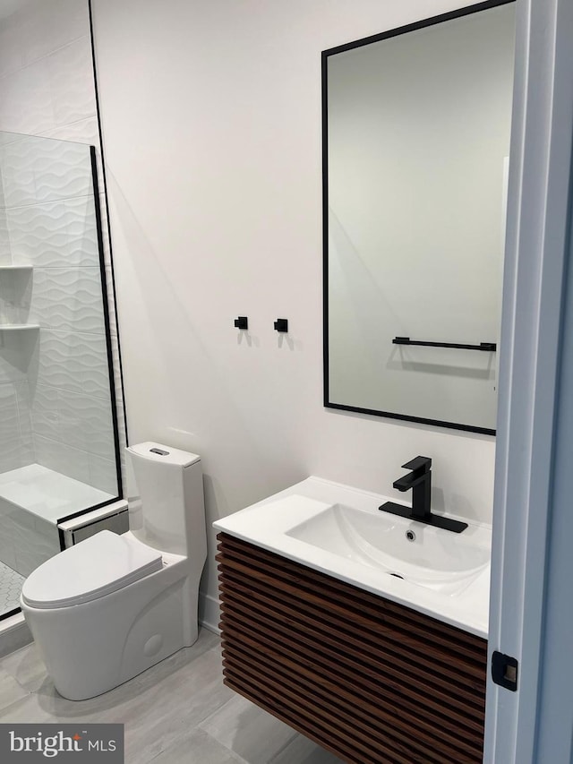 bathroom featuring a shower stall, toilet, and vanity