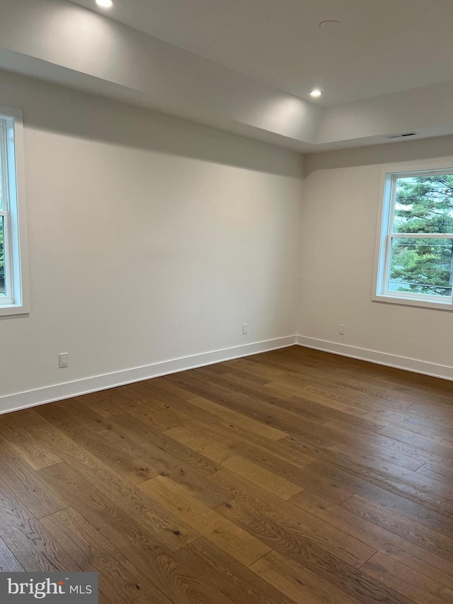 spare room with dark wood-style floors, visible vents, and baseboards