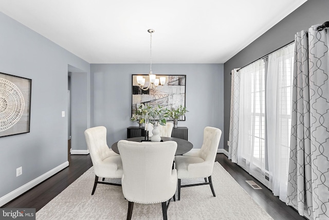 dining space featuring visible vents, baseboards, an inviting chandelier, and wood finished floors