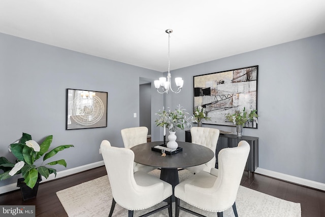 dining space featuring a chandelier, baseboards, and wood finished floors